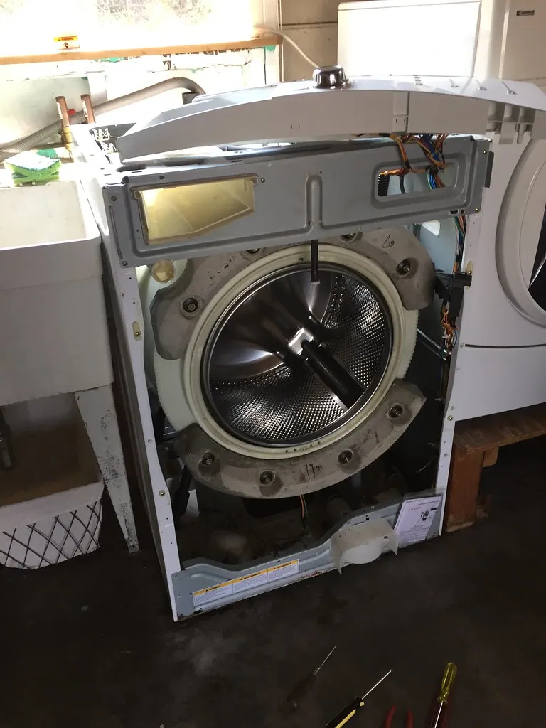 A washing machine being repaired by a technician